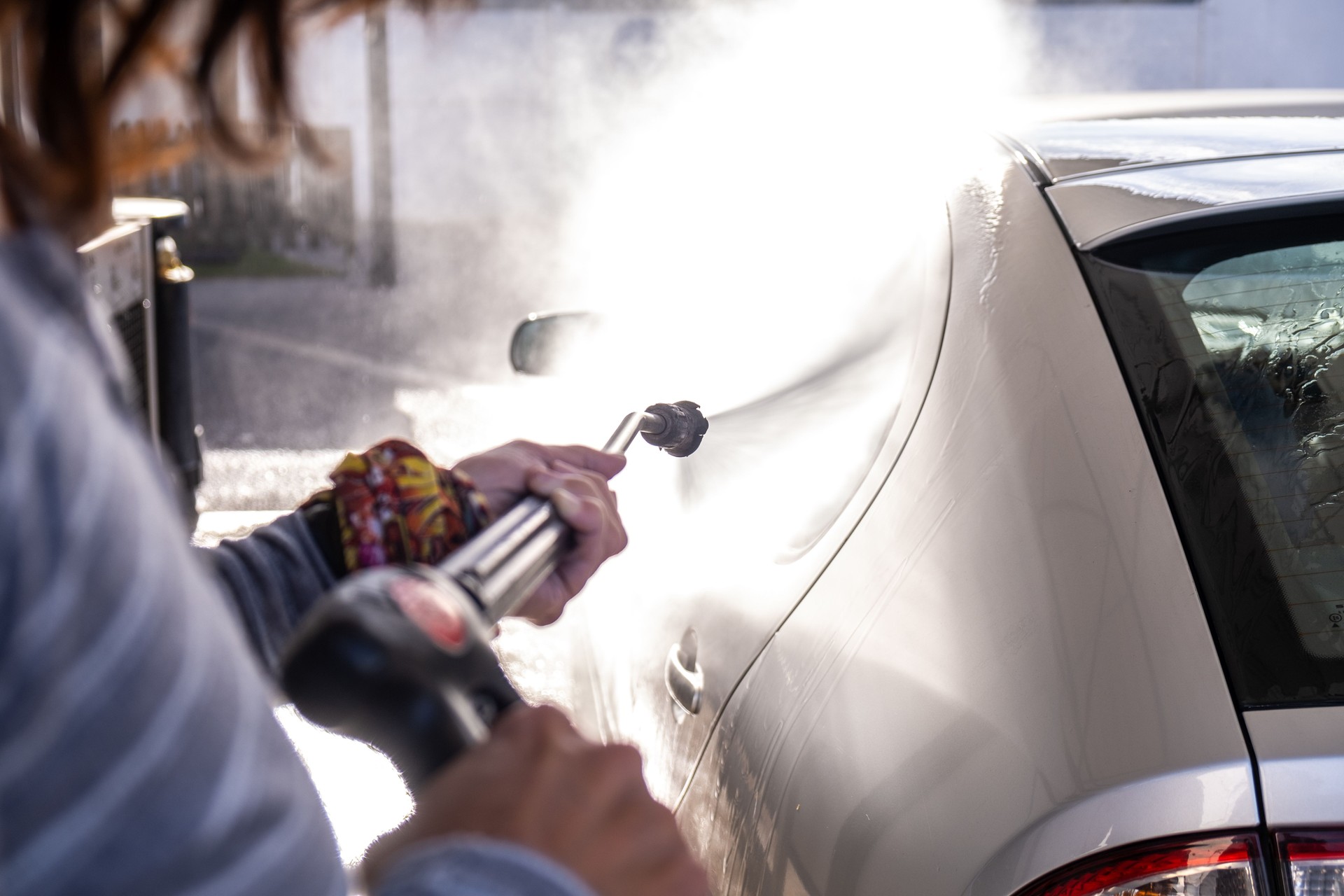 Woman washes her car with a pressure washer